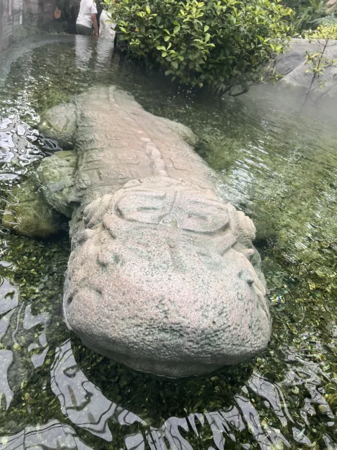 浅水与绿植间的古老石像